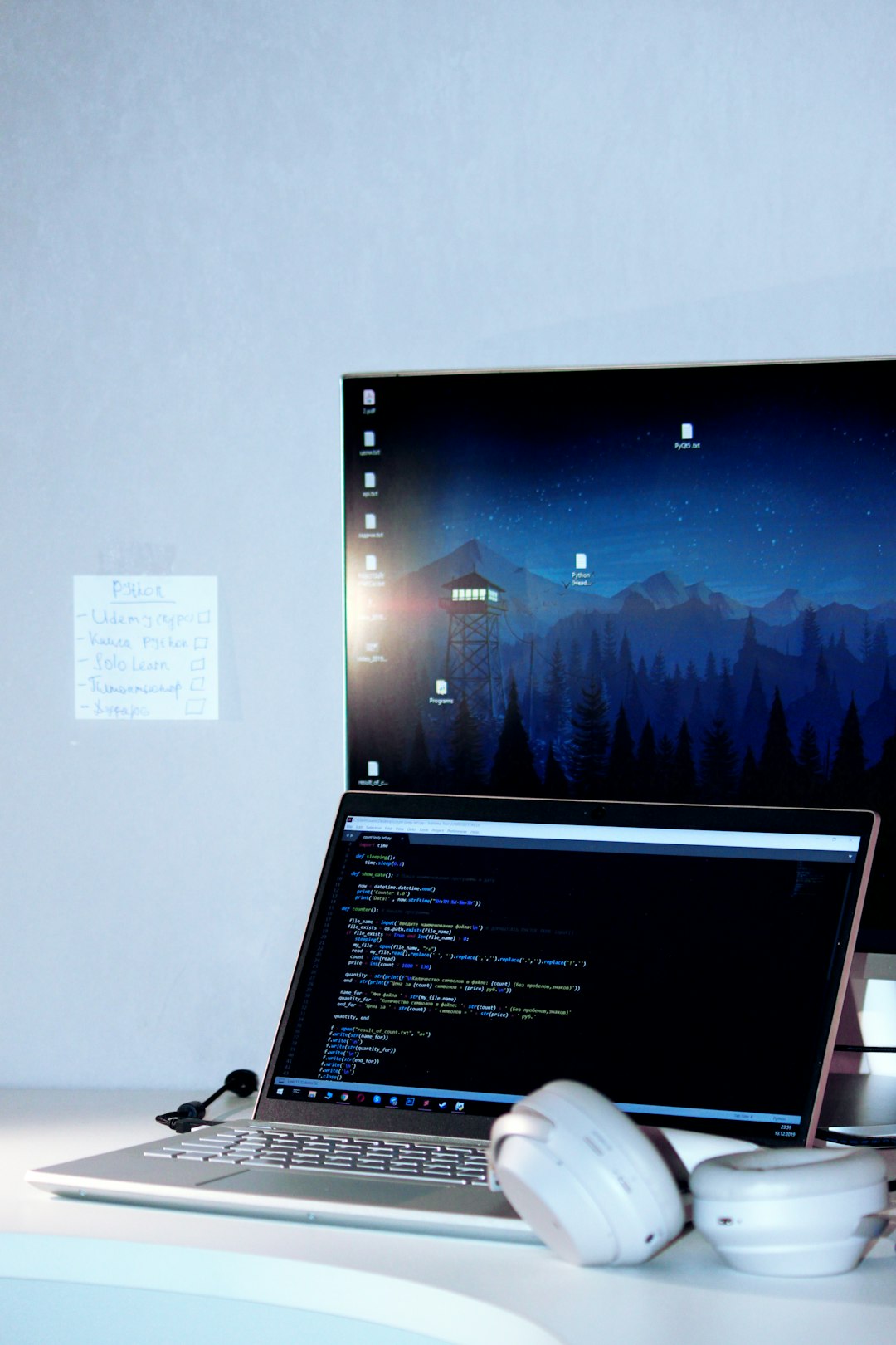 laptop near to a crew monitor with code of python